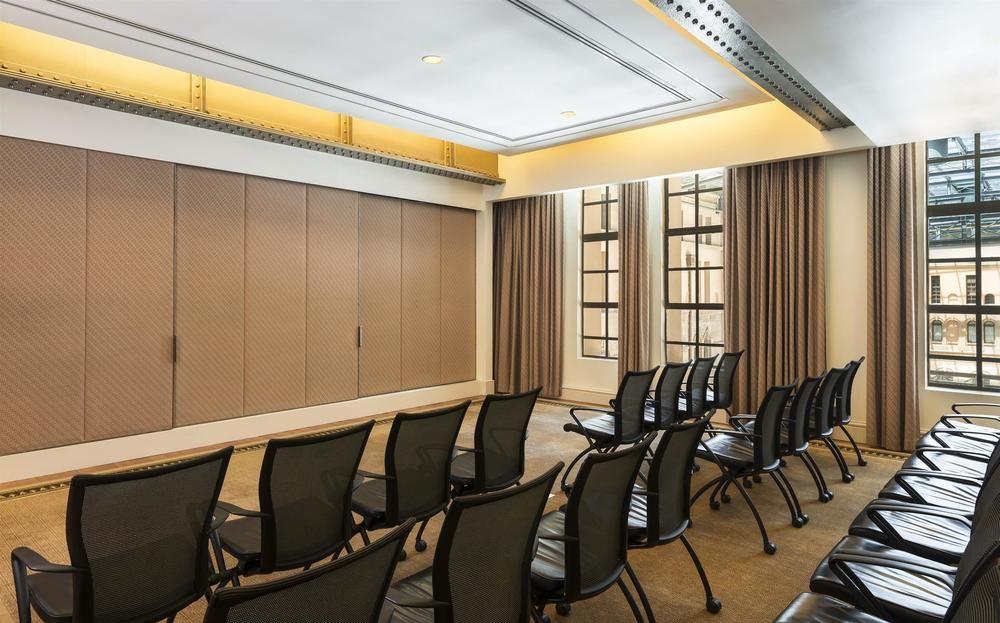 The Fullerton Hotel Sydney Eksteriør bilde The photo shows a modern conference room or meeting space. There are several rows of black chairs arranged facing a wall. The walls appear to have a beige tone with large windows adorned with curtains, allowing natural light to enter. The ceiling is 