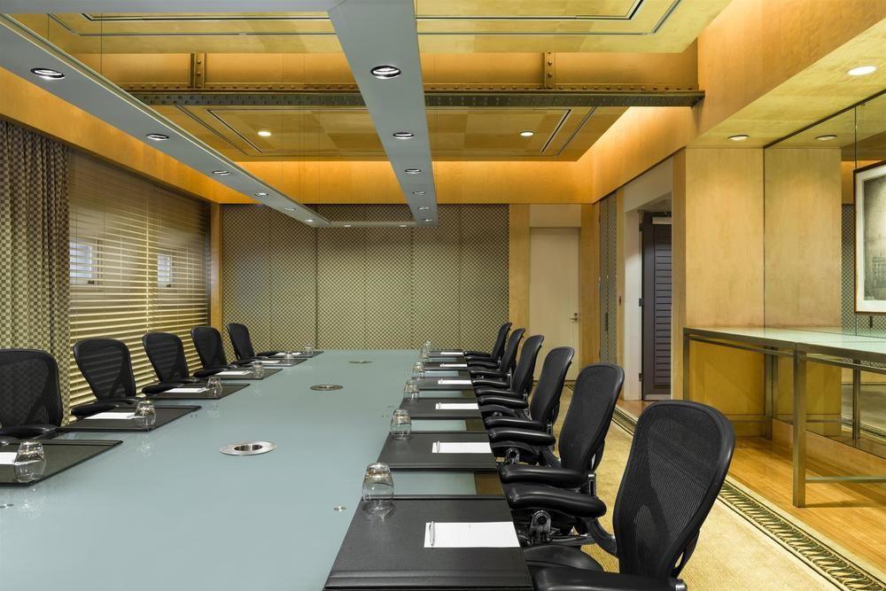 The Fullerton Hotel Sydney Eksteriør bilde The photo shows a modern conference room with a long, rectangular table at the center. There are several ergonomic office chairs lined up on either side of the table. The tabletop appears to be a light-colored glass or a similar material, and it has 