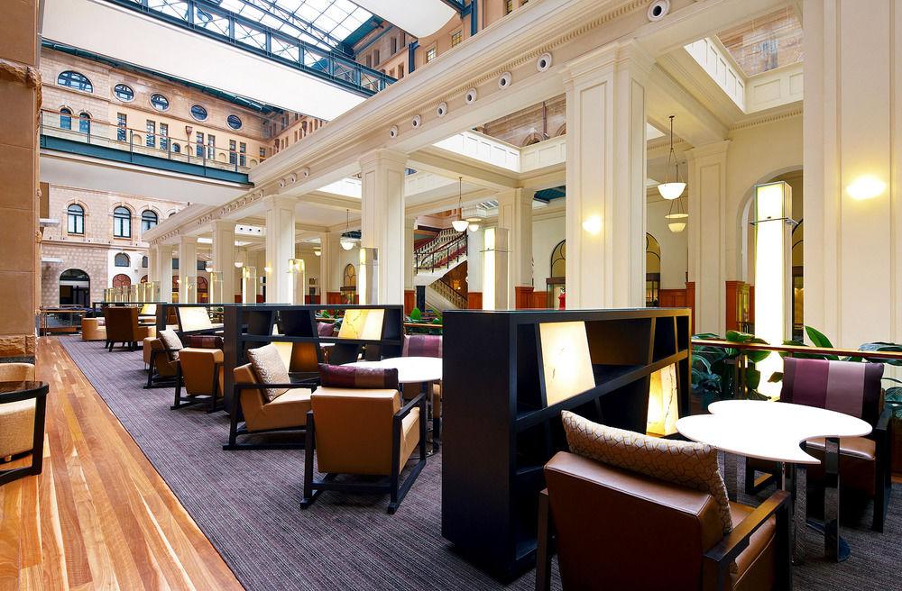 The Fullerton Hotel Sydney Eksteriør bilde The photo features a spacious and well-lit interior of a lounge or café area, characterized by high ceilings and large windows that allow natural light to flood the space. The design includes elegant architectural details, such as tall columns and an