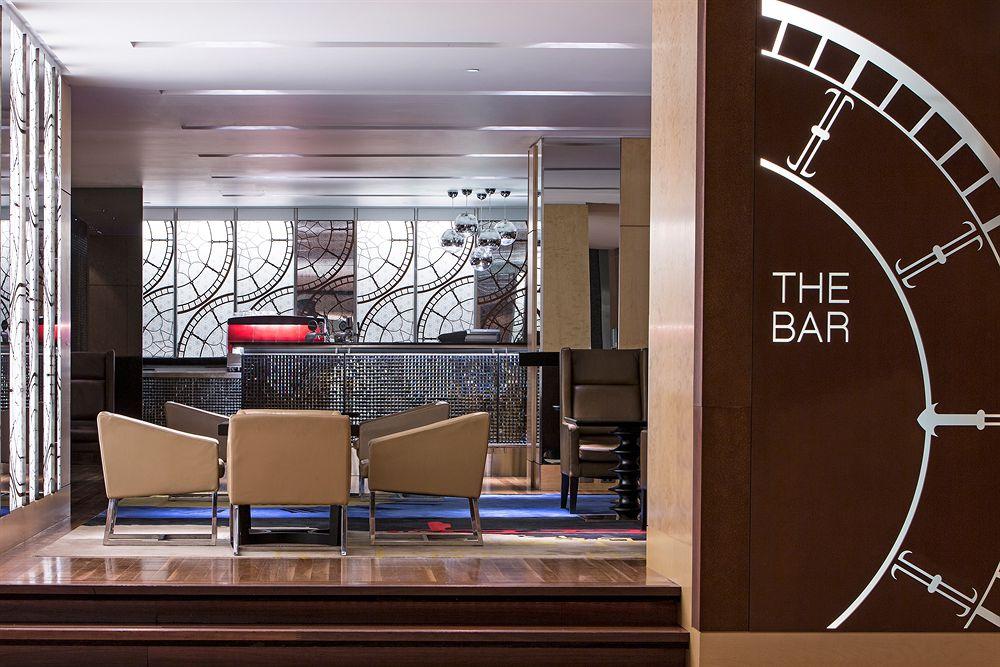 The Fullerton Hotel Sydney Eksteriør bilde The photo shows a modern bar area. On the left side, there's a stylish sign that reads "THE BAR," integrated into a decorative design. In the center, behind a sleek counter, there appears to be a mirror with intricate patterns. The bar itself has a r